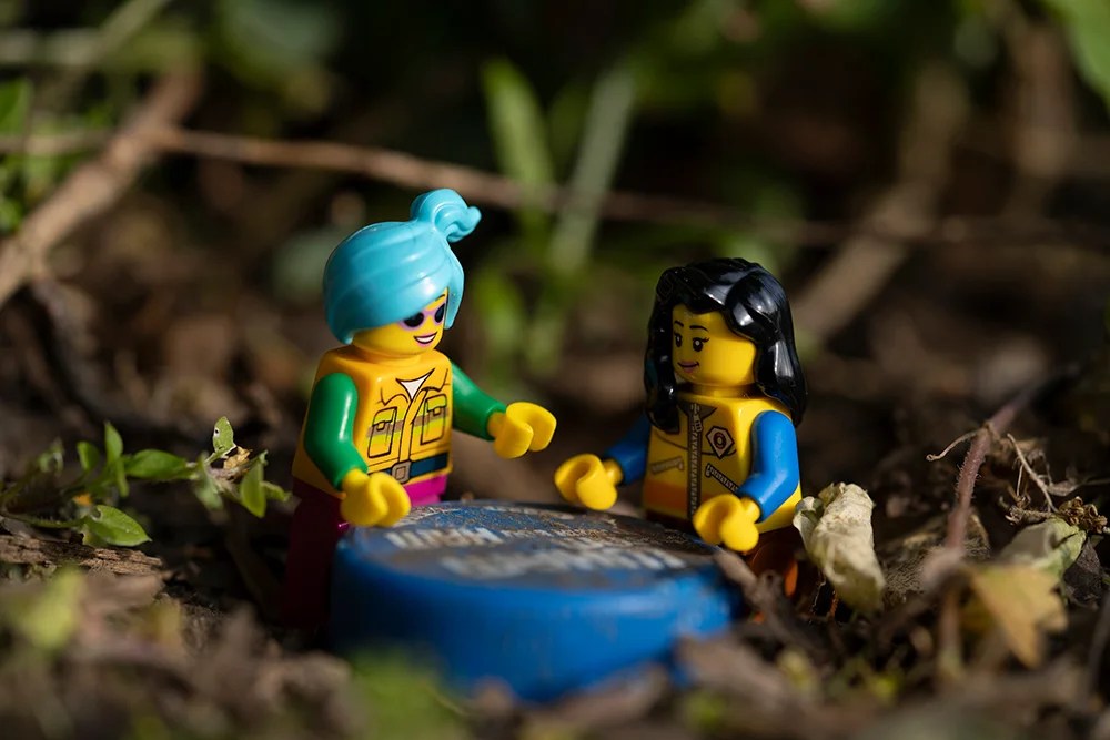 Two Lego figures around a bottle cap