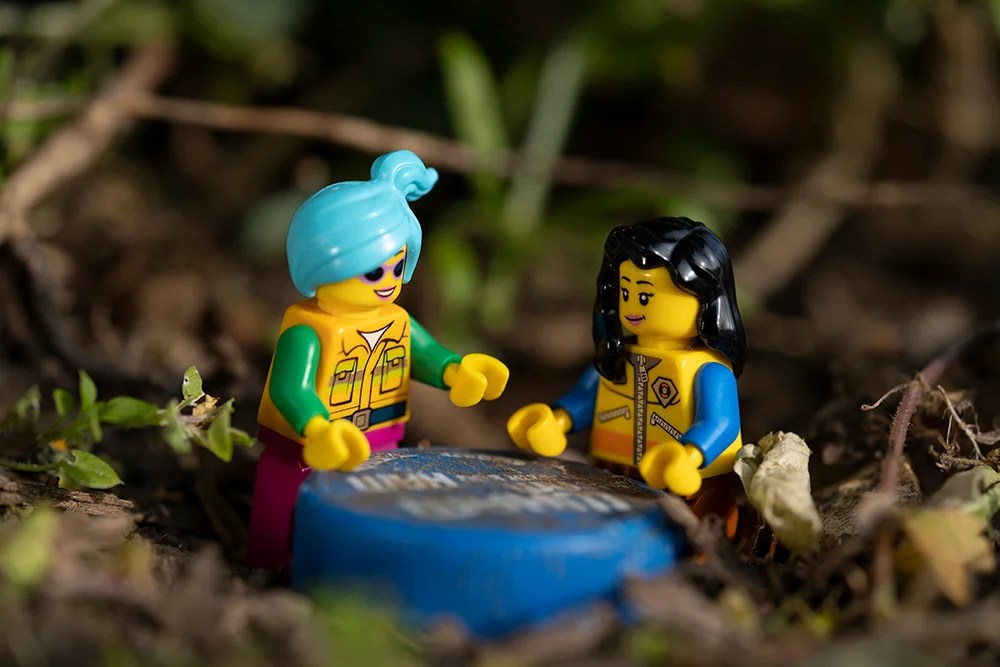 Two Lego figures sat around a bottle cap