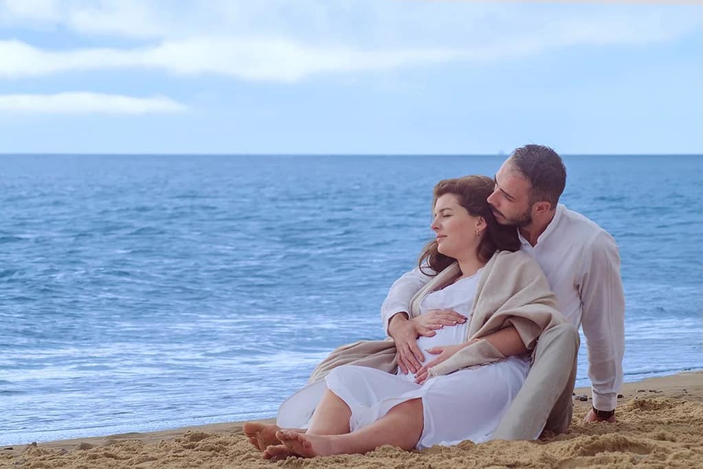 A man and woman sat together on the beach