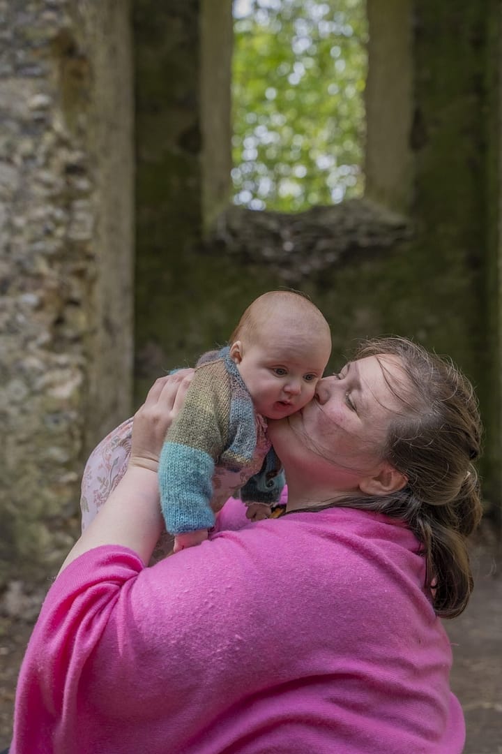 A mother holding and kissing her child, during one of our photography packages