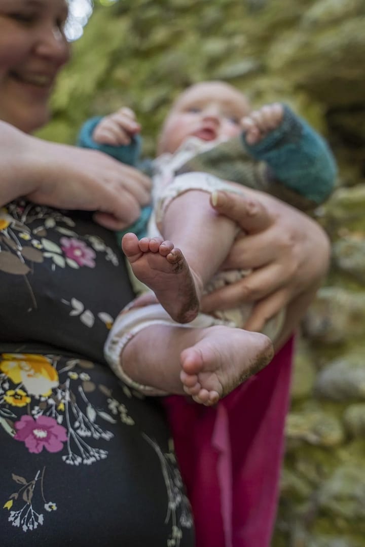 A mum holding her baby, with their dirty feet visible, family photography portfolio