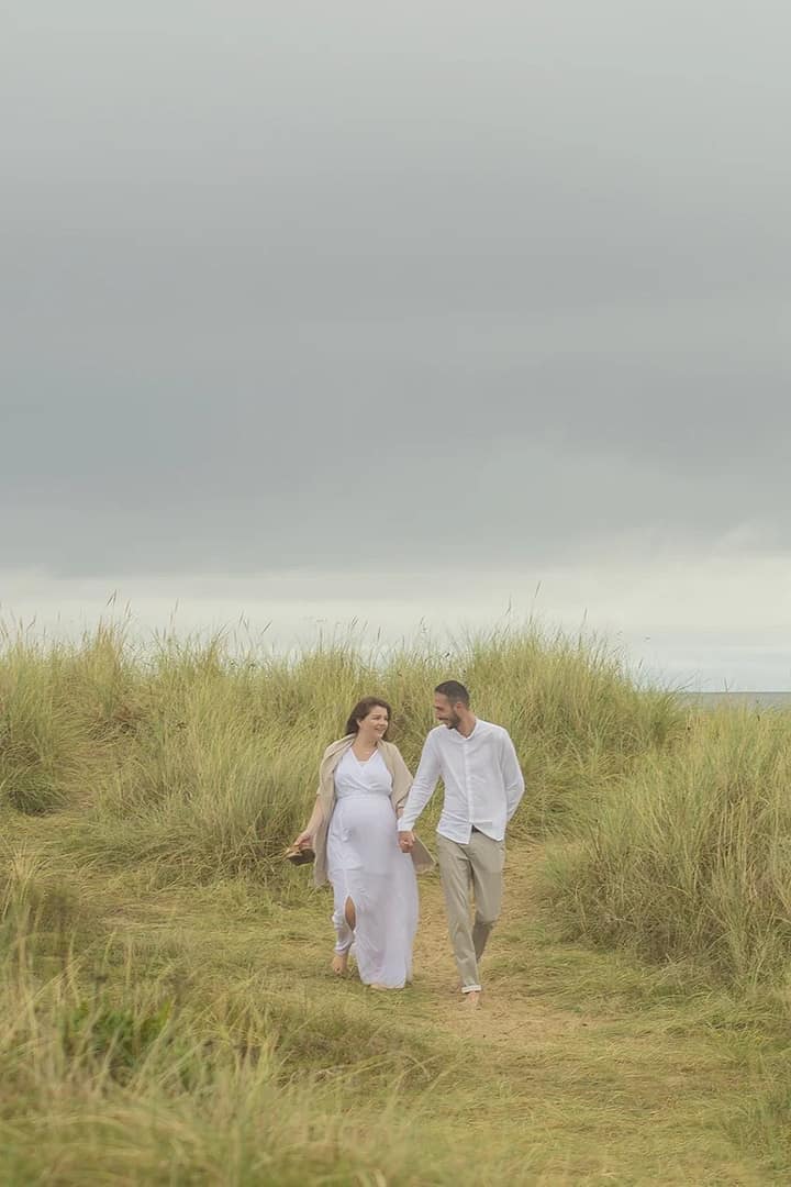 A couple walking through the dunes holding hands